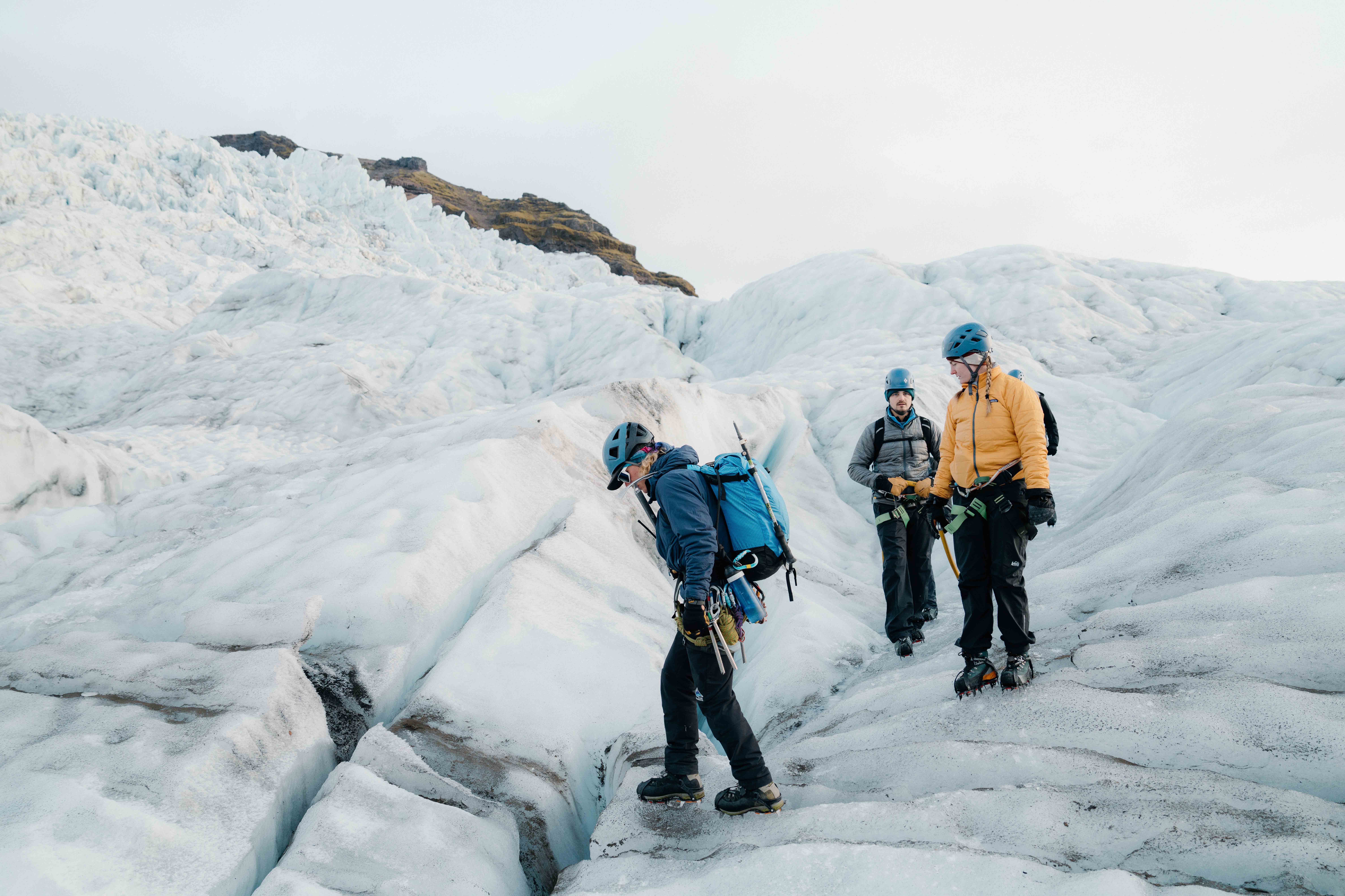 Three people in mountaineering gear walk across a glacier